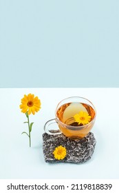 Cup Of Herbal Tea On Stone With Orange Calendula Flowers On Blue Background. Calming Drink Concept. Trendy Still Life.