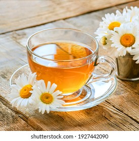 a cup of herbal tea on a wooden table, wild chamomile flowers, a warm relaxing drink made from natural ingredients