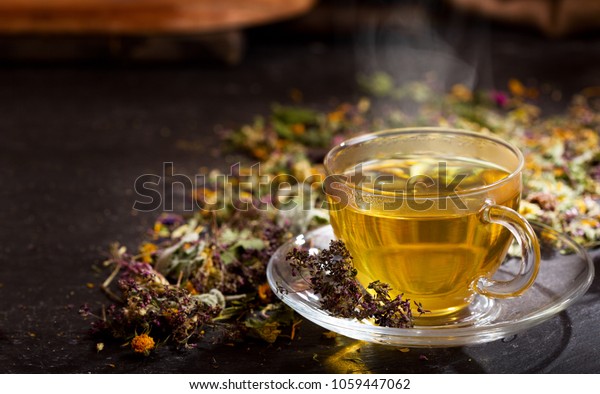 Cup\
of herbal tea with various herbs on dark\
background