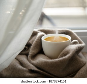  cup of hot aromatic coffee and cashmere scarf on the windowsill on winter morning. selective focus .High quality photo