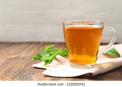 Cup with hot aromatic mint tea on wooden table