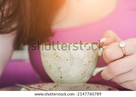 A cup of hot cappuccino in a woman's hands close