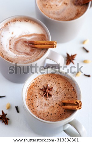 Cup of hot chai latte with spices like cinnamon, cardamon, cloves, star anise as a sweet warm winter dessert drink