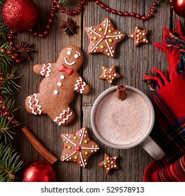 Cup of hot chocolate or cocoa with gingerbread man, warm scarf composition in fir tree decorations frame on vintage wooden table background. Square view - Powered by Shutterstock