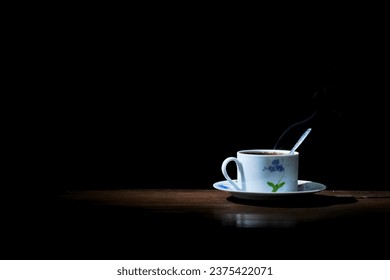 a cup of hot coffee brewed with a spoon on a wooden table on a black background - Powered by Shutterstock