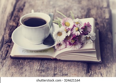 A cup of hot coffee, flowers and book. Romantic background with retro filter effect