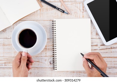 Cup of hot coffee and man hand writing notebook on wood table background.copy space - Powered by Shutterstock