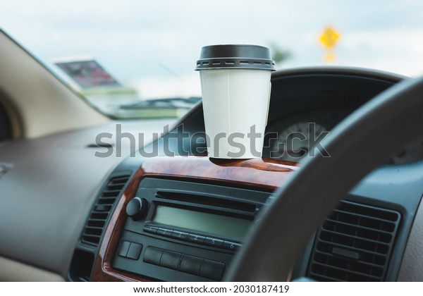 A cup of hot coffee put on the car\
console. Drinking coffee while travel by\
car.