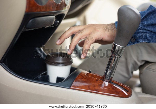 A cup of hot coffee put on the car\
console. Drinking coffee while travel by\
car.