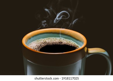 Cup of hot coffee and steaming on black background