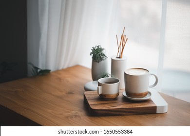 cup of hot coffee and tea on wood table besides window