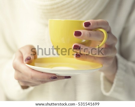 Cup with a hot drink in female hands close up. Soft style toned photo. 