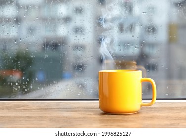 Cup of hot drink near window on rainy day. Space for text - Powered by Shutterstock