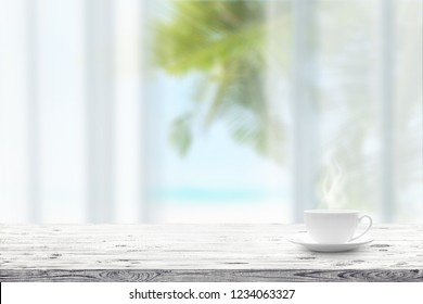 Cup with hot drink on wooden table and blue seascape on a background. Beauty nature background