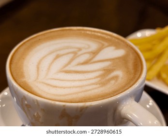 a cup of hot mocaccino, featuring a leaf-patterned latte art design.