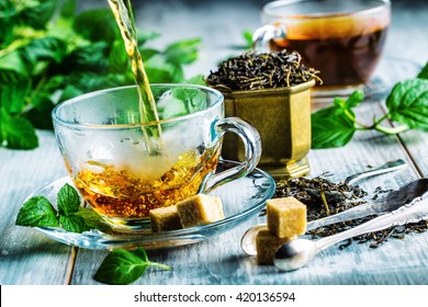 Cup of hot tea cane sugar dry tea leaves and mint herb.
