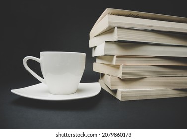 Cup of hot tea or coffee and stack of books.