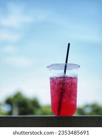 a cup of ice sweet red soda with the view of blue sky background - Shutterstock ID 2353485691