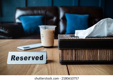 A Cup of Iced Coffee on a Reserved Table at Restaurant with Leather Sofa on the Background - Powered by Shutterstock