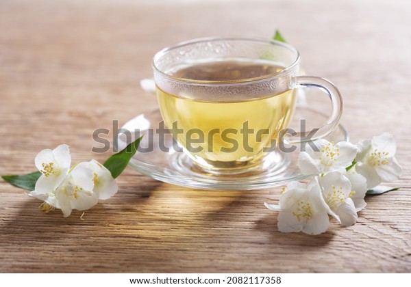 cup\
of jasmine tea and jasmine flowers on a wooden\
table