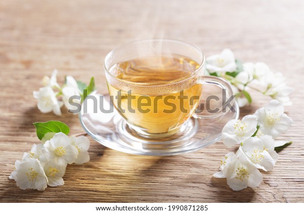 cup of jasmine tea and fresh jasmine flowers on a\
wooden table