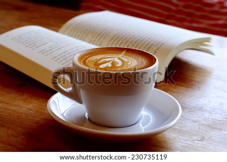 cup of latte or cappuccino coffee with a book in coffee shop with vintage retro filter effect