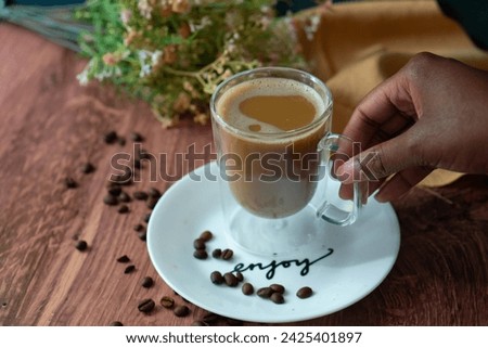 A cup of light coffee being held in a lifestyle setting