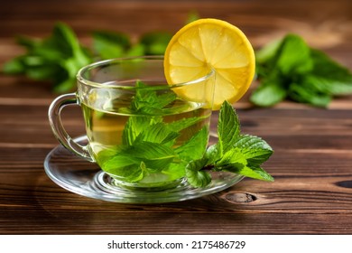Cup of mint tea and a bunch of mint and lemon on the table.