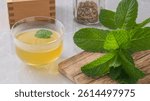 Cup with mint tea and mint plant on cutting wood
