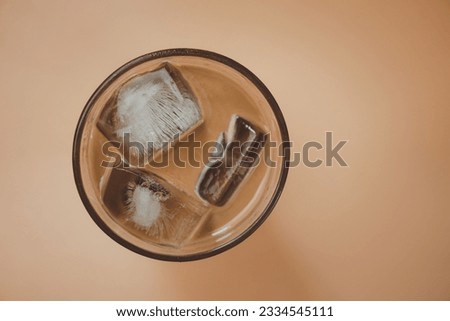 A cup of Mocha coffe filled with ice cubes. Refreshing summer drink.