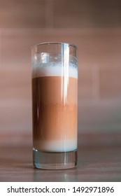 cup of multilayer coffee in a glass cup on brick background