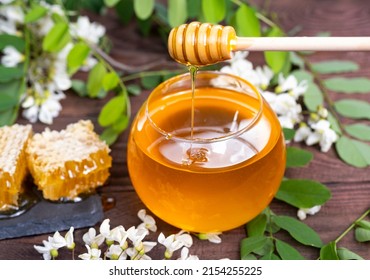 A cup with natural honey, honey in combs against the background of acacia flowers on a wooden table. The concept of wild bees honey and healthy sweets. - Shutterstock ID 2154255225