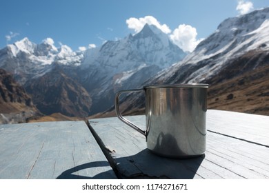 Cup On Table With Himalaya Mountains In The Background Showcasing A Life Of Adventure And Thrill Seeking.