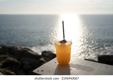 Cup orange juice on top table seaside during sunset sky daylight. Close-up Fresh orange cocktail in glass cafe holiday coconut trees background. - Shutterstock ID 2196943067