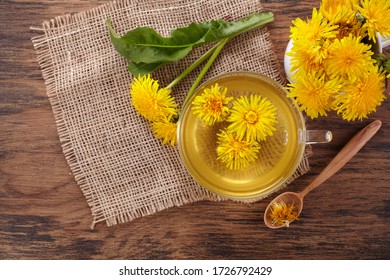 Cup ph healthy dandelion tea on vintage wooden background. Fresh herbs.