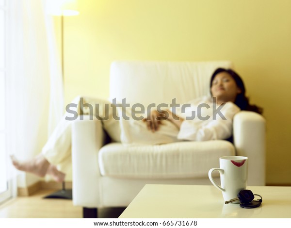cup with\
printed lip and woman resting on arm\
chair