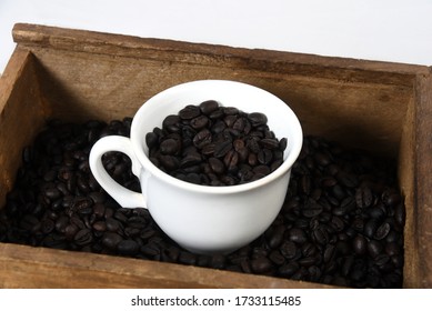 cup with roasted coffee beans inside, on the table with roasted beans