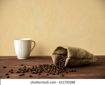 Cup With Saucer And Bag With Coffee Beans On The Wooden Table