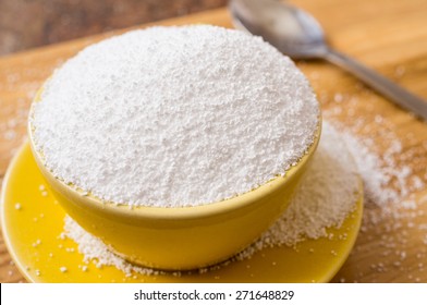 Cup of sorbitol, a natural sweetener on the table next to a spoon. Closeup