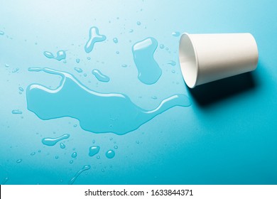 Cup with spilled water on a blue background. Abstract light. Ice concept for drinks. Banner. Flat lay, top view