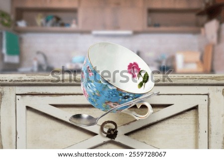 A cup and a spoon are falling down from table in the kitchen