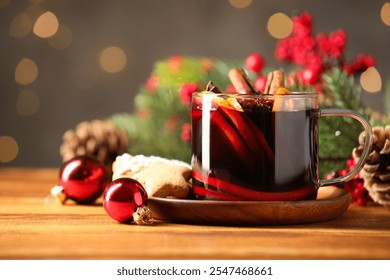 Cup of tasty mulled wine with spices and Christmas decor on wooden table against blurred lights, closeup - Powered by Shutterstock