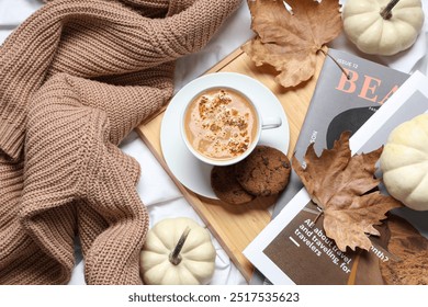 Cup of tasty pumpkin coffee with cookies, magazines and warm sweater on bed at home, top view - Powered by Shutterstock