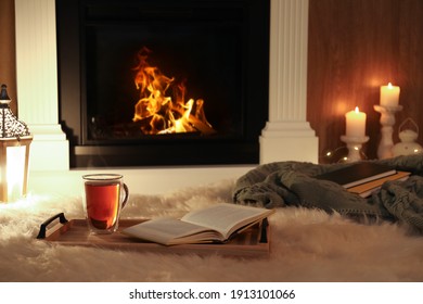 Cup Of Tea And Book On Fuzzy Rug Near Fireplace At Home. Cozy Atmosphere