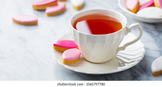 Cup of tea with calissons, traditional French Provence sweets on marble table background. Copy space.