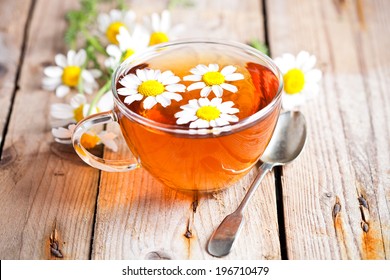 cup of tea with chamomile flowers on rustic wooden background