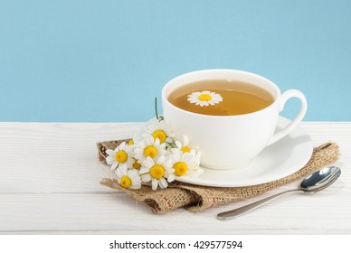Cup of tea and chamomiles on wooden background