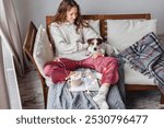 Cup of tea or coffee and chill. Woman sitting on couch drinking hot cacao and enjoying morning, being in dreamy and relaxed mood. Girl play with dog at home