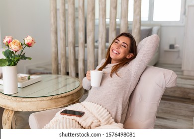 Cup Of Tea, Coffee And Chill. Woman Lying On Couch Drinking Hot Coffee And Enjoying Morning, Being In Dreamy And Relaxed Mood. Girl Covered In Blanket Takes Break At Home