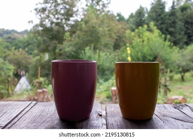 Cup Of Tea Or Coffee On The Table Outdoors. Two Colorful Mugs On Wooden Table In Summer, Autumn Forest Landscape Nature Background. Vacation, Travel, Picnic, Stress Relief, Camping Concept